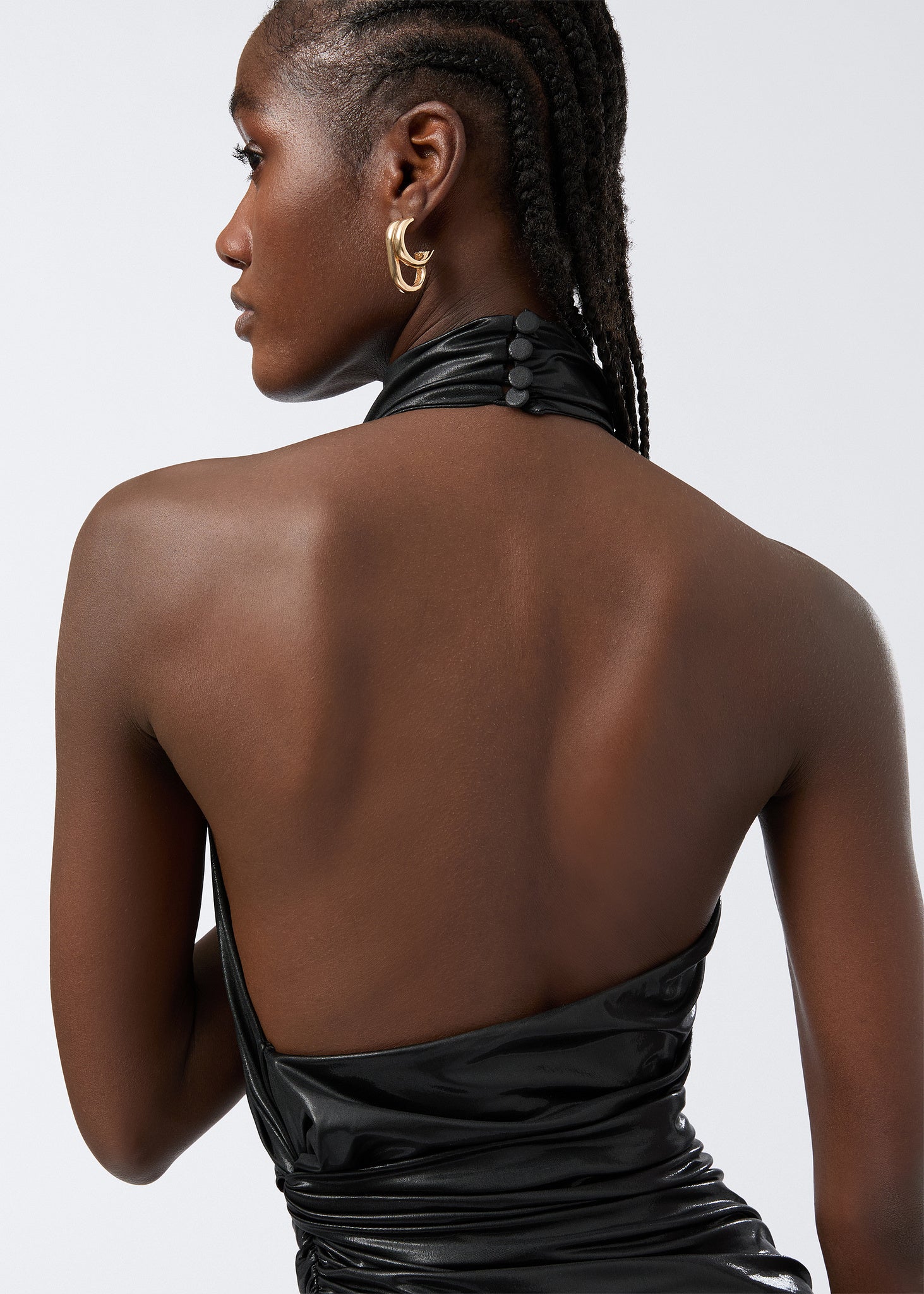 Detail view showing the dramatic open back and high-buttoned turtleneck of the Stella Maxi Dress in black shiny liquid jersey, highlighting its fitted draped style.