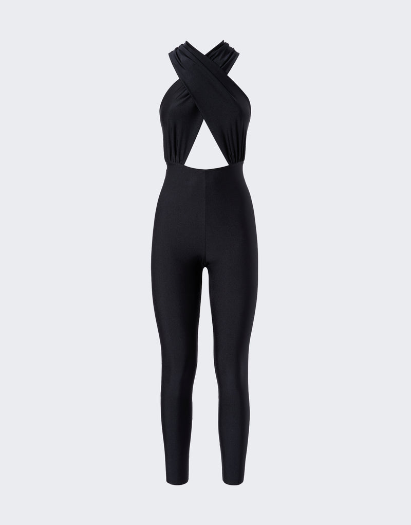 Frontal view of the Hola Jumpsuit showing a black shiny lycra halterneck design with overlapping straps, a triangular front cut-out, and slim, fitted legs.