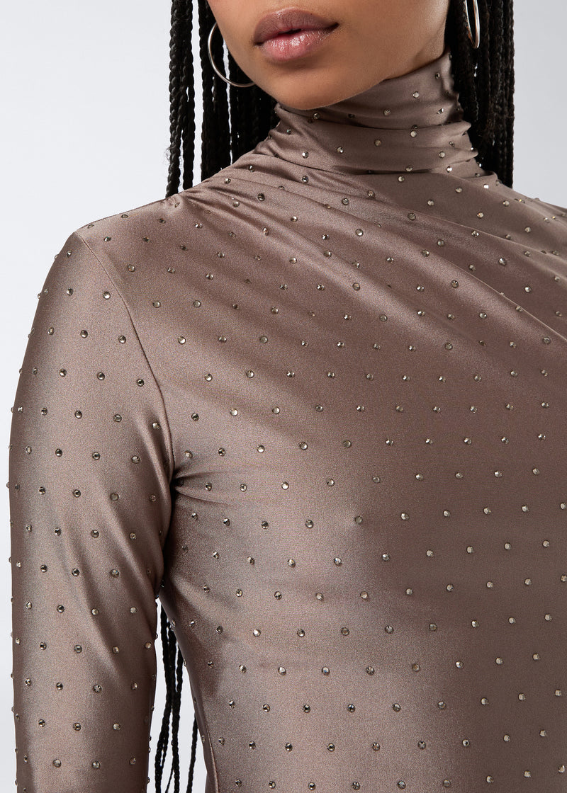 
                          Detail view shows the Oleandra Crystal Mini Dress in greige shiny lycra, featuring a turtleneck, long sleeves, and tone-on-tone crystals for a sparkling finish.
                        