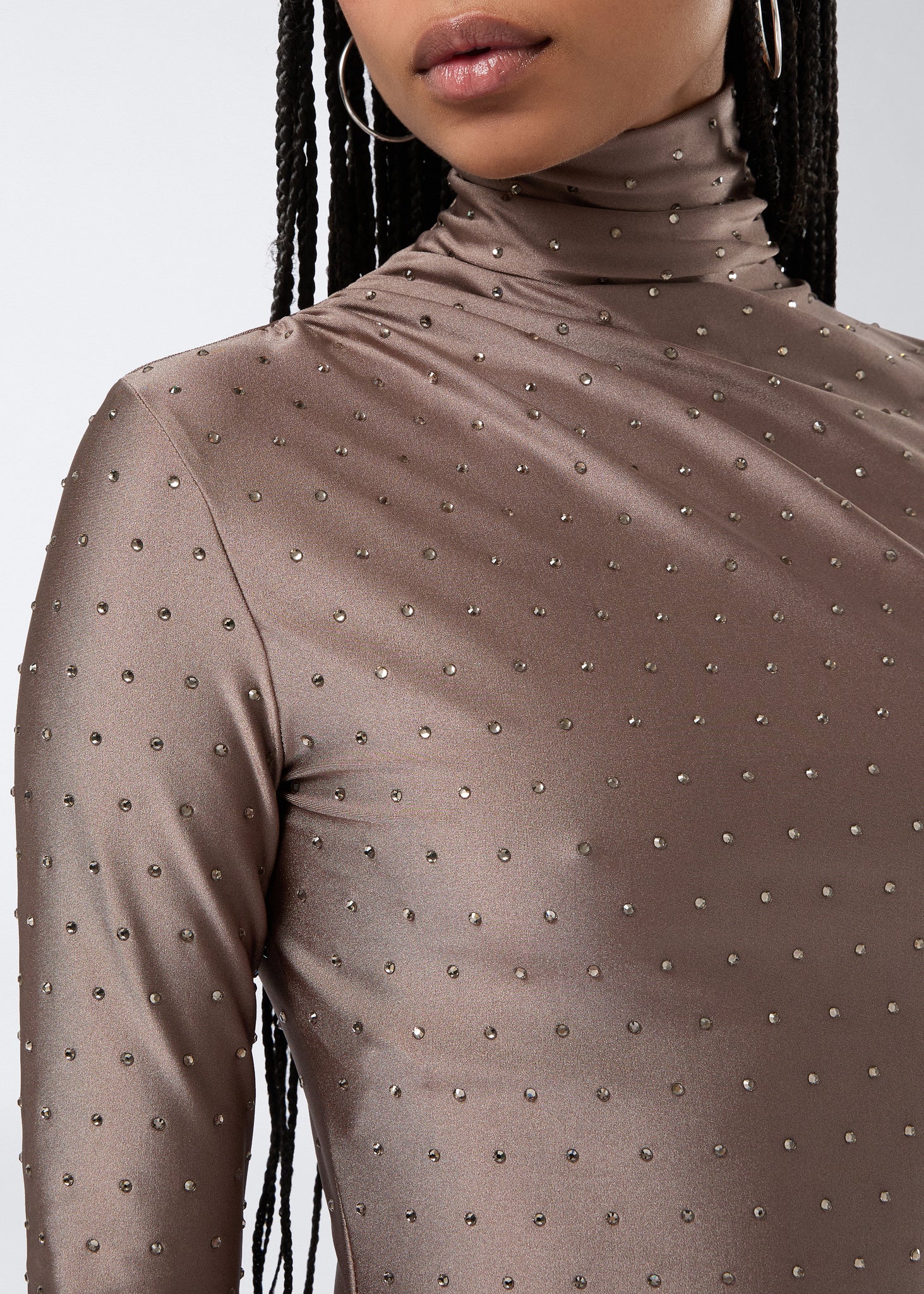 Detail view shows the Oleandra Crystal Mini Dress in greige shiny lycra, featuring a turtleneck, long sleeves, and tone-on-tone crystals for a sparkling finish.