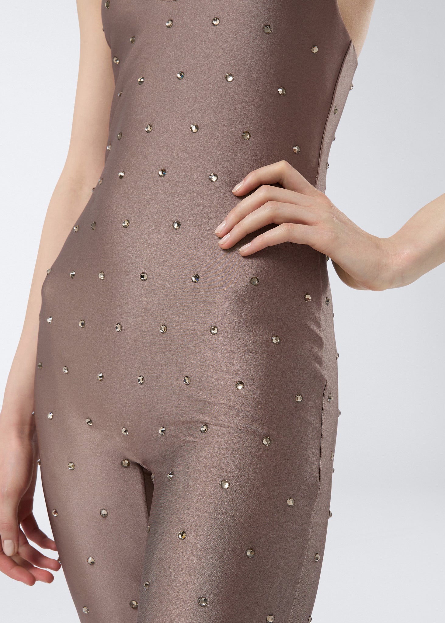 Detail view showing the Tess Crystal Jumpsuit in greige shiny lycra, decorated with evenly spaced tone-on-tone crystals and featuring a fitted silhouette.