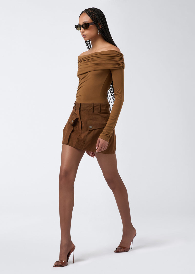 
                          Side view of a woman wearing the Xandra Mini Skirt in cigar-colored stone-washed cotton, featuring patch pockets with snap buttons and belt loops.
                        