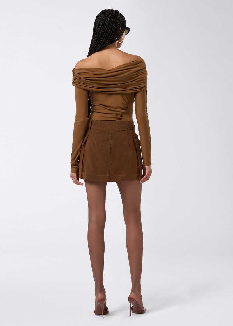 
                          Rear view shows model wearing the Xandra Mini Skirt in cigar-colored stone-washed cotton, featuring a fitted waist, belt loops, and two side patch pockets.
                        