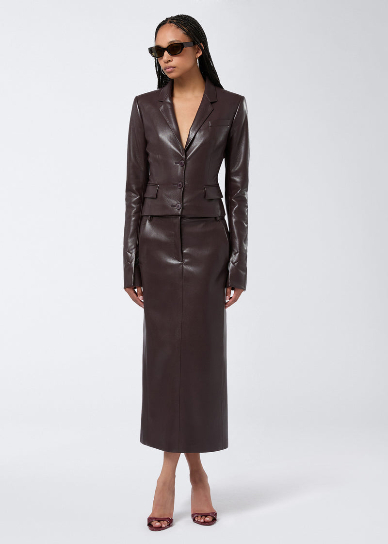 
                          Frontal view of a model wearing the Xania Midi Skirt in cabernet vegan leather, featuring a high waist, central seam, and paired with a matching jacket.
                        