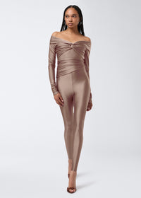 Frontal view of a model wearing Vicky Leggings in a greige shiny lycra fabric, featuring high waist, full-length fit, and draped detail around the waist.