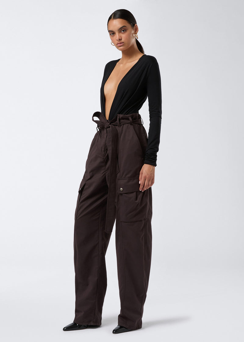 
                          Frontal view of a person wearing Xandra Maxi Pants in dark brown suede-touch nylon, featuring a relaxed silhouette, cargo-style button pockets, an adjustable belt, and an elasticated back waist.
                        