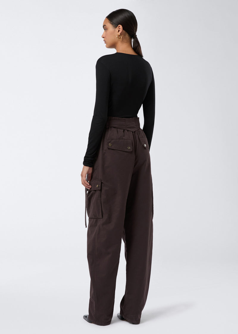 
                          Rear view shows model wearing Xandra Maxi Pants in dark brown suede-touch nylon with buttoned thigh and back pockets, elasticated waist, and relaxed fit.
                        
