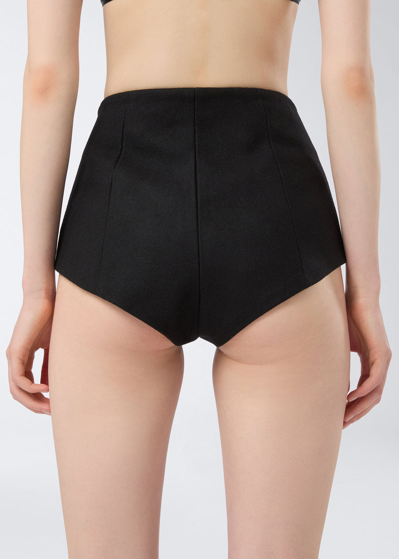 
                          Rear view of a person wearing Tami Culottes, tailored from black felted wool with a high waist and structured finish, ending at the upper thighs.
                        