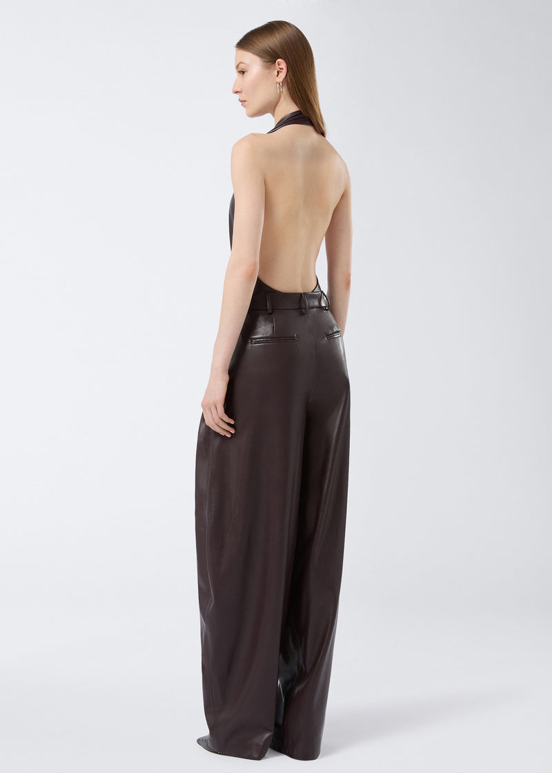 
                          Rear view shows a model wearing cabernet-colored Tracy Maxi Pants in vegan leather, featuring belt loops, back slit pockets, and a wide flared silhouette.
                        