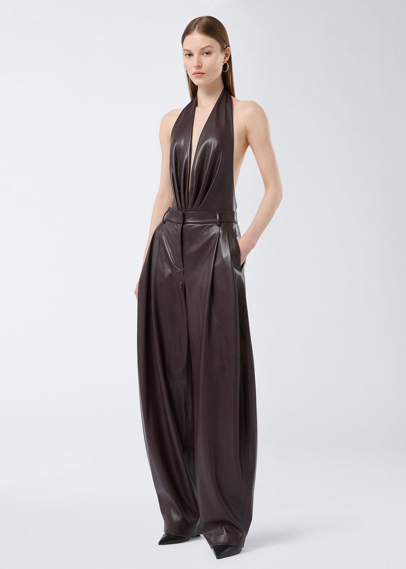 
                          Frontal view shows a model wearing the Tracy Maxi Pants in cabernet-colored vegan leather, featuring a flared, pleated, and tailored design with belt loops and side slit pockets.
                        