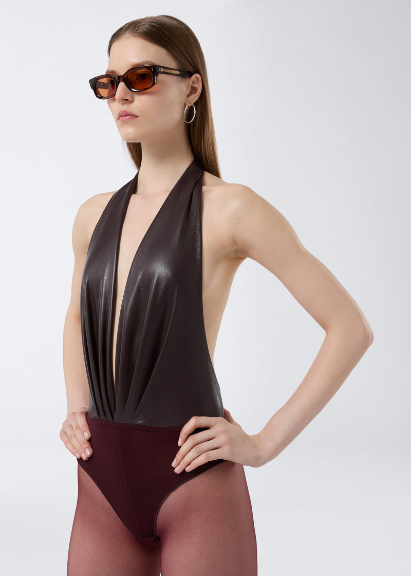
                          Frontal view of a woman wearing the Zendaya Bodysuit in cabernet vegan leather, featuring a plunging V-neck, halterneck strap, and deep front pleats.
                        