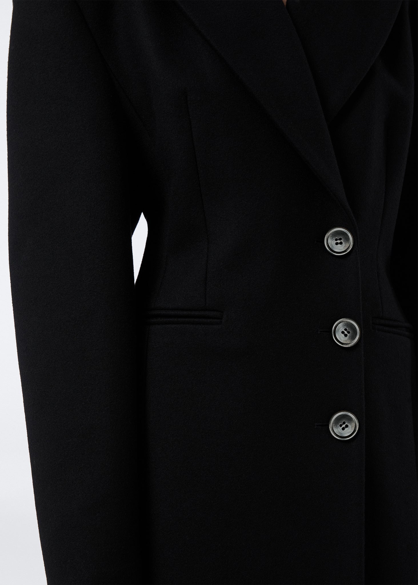 Detail view of the Ottavia Coat showcasing the black felted wool fabric, pointed lapel collar, and three front buttons for single-breasted closure.