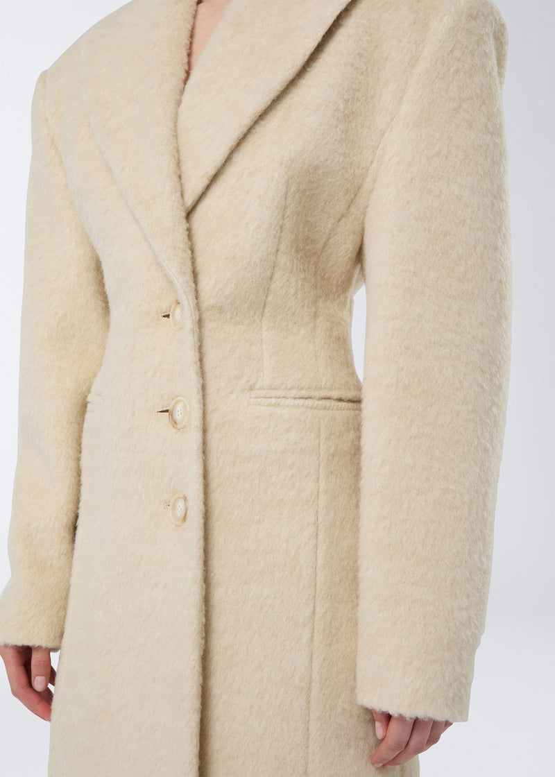 
                          Frontal view showing the Ottavia Coat, an ivory soft wool twill women&#39;s coat with padded shoulders, peaked lapel collar, defined waist, and three buttons.
                        