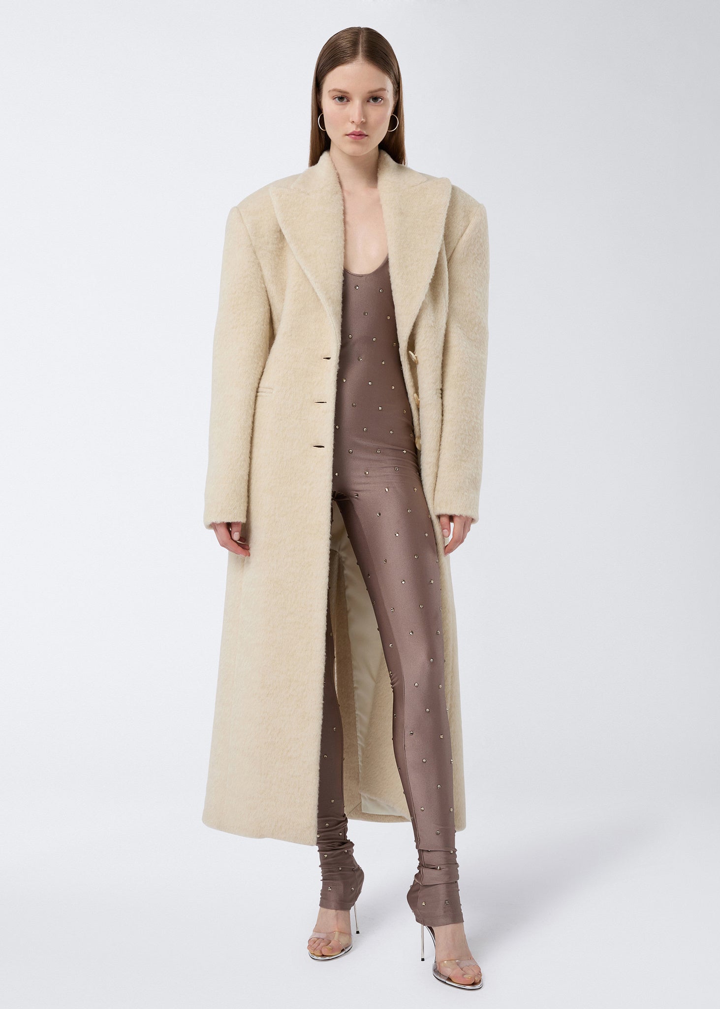 Frontal view of Ottavia Coat, an ivory soft wool twill women’s coat with padded shoulders, peaked lapel collar, defined waist, and long length.