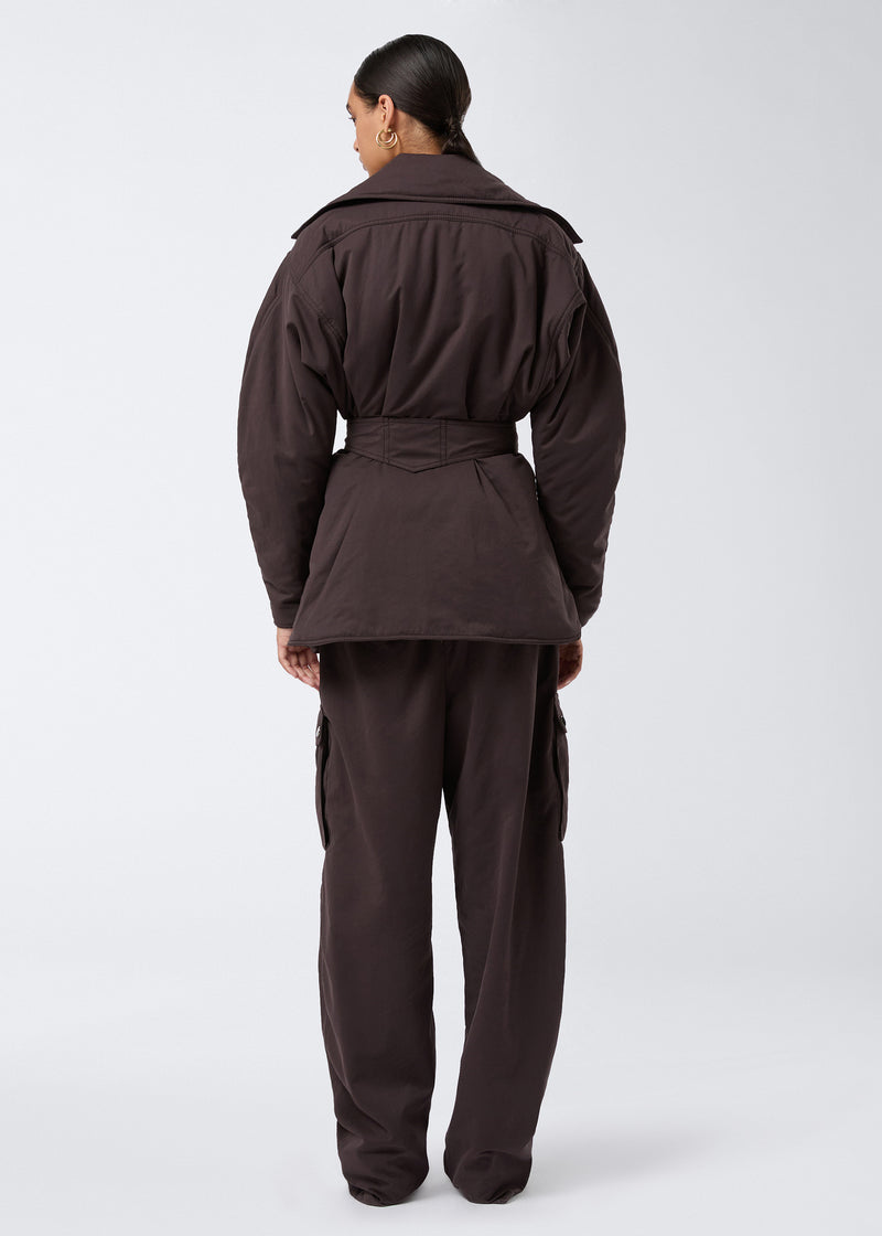 
                          Rear view shows a model wearing the Xandra Jacket in dark brown suede-touch nylon, featuring an oversized collar and a sewn-on matching belt at the back.
                        