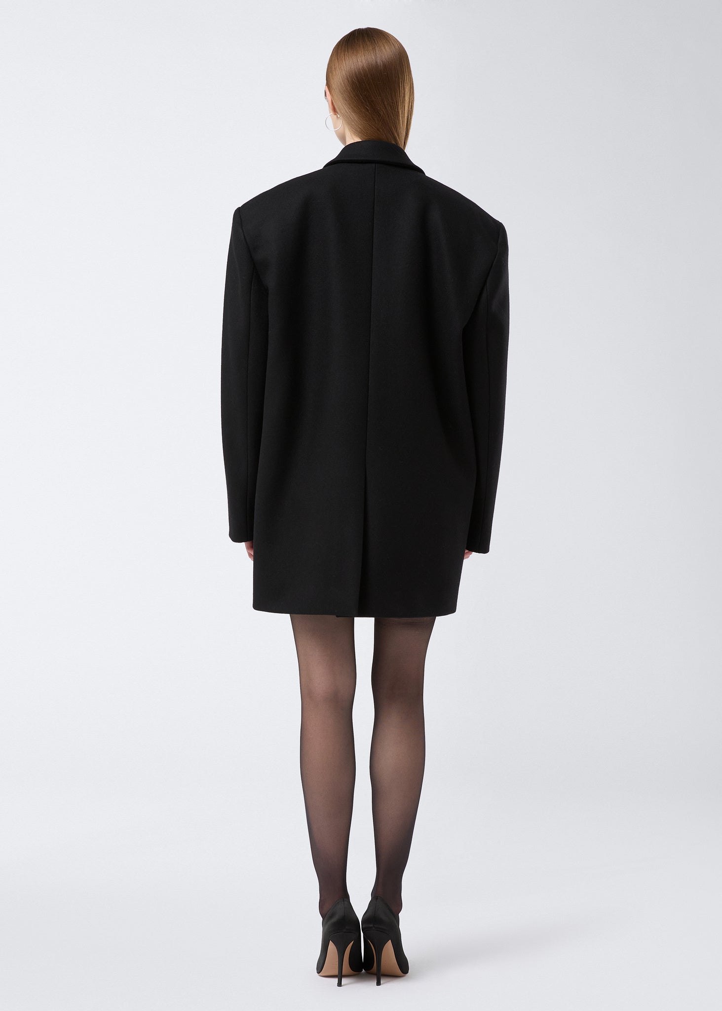 Rear view showing a model wearing the Teresa Blazer in black felted wool, displaying an oversized fit with a back vent detail.