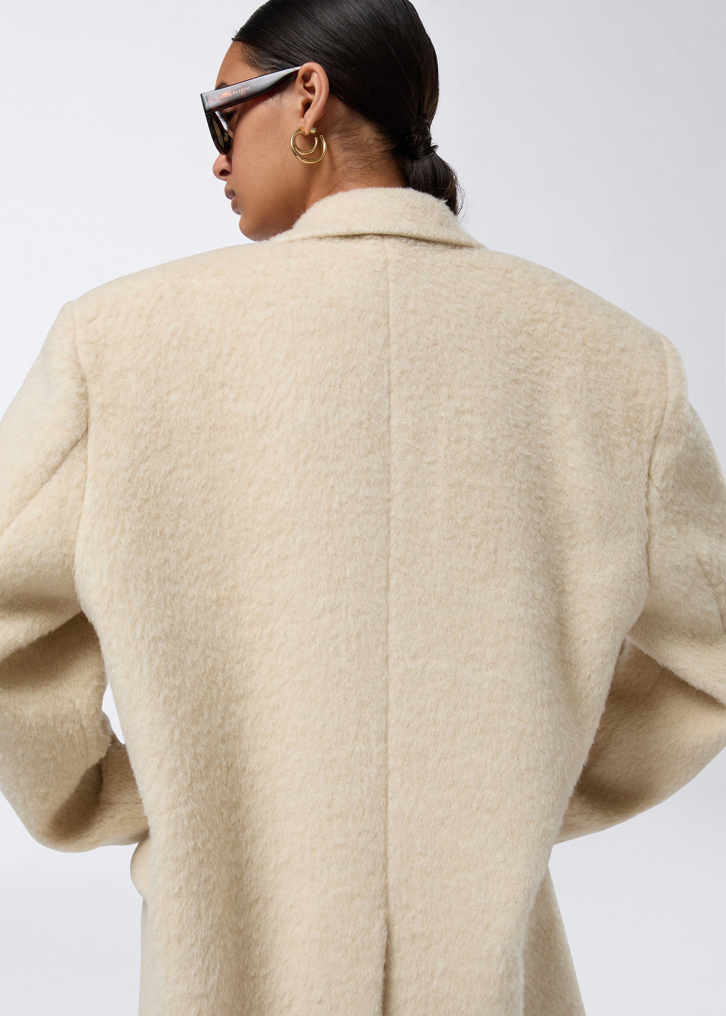 Rear view of a woman wearing the Teresa Blazer in ivory soft wool twill, highlighting the fluffy finish, slightly padded shoulders, and clean back seam.
