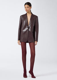 Frontal view of a woman wearing the Guia Blazer in cabernet vegan leather, featuring an oversized fit, notched lapel, single button closure, and chest welt pocket.