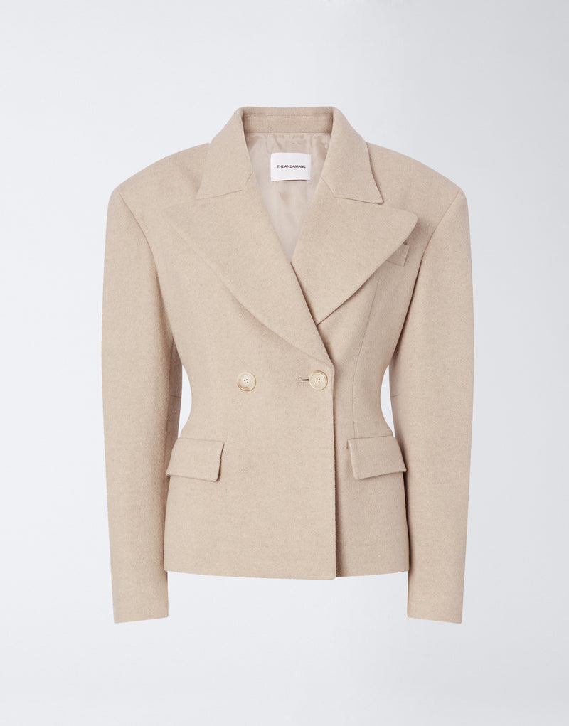 
                          Frontal view of the Tillie Blazer in sand-colored soft felted jersey, featuring a double-breasted closure, wide lapel, flap pockets, and buttoned cuffs.
                        