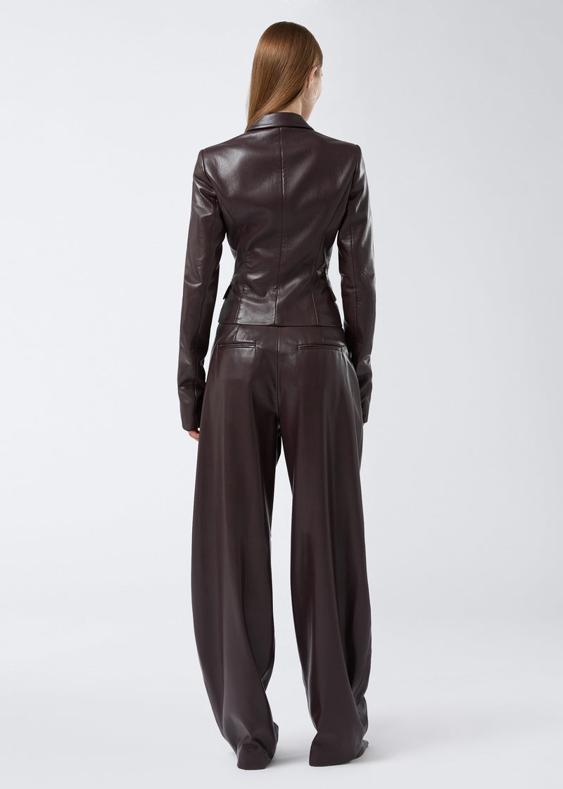
                          Rear view shows a woman wearing the Zefira Blazer in cabernet vegan leather, featuring a fitted, cropped silhouette with long sleeves and subtle seam detailing.
                        