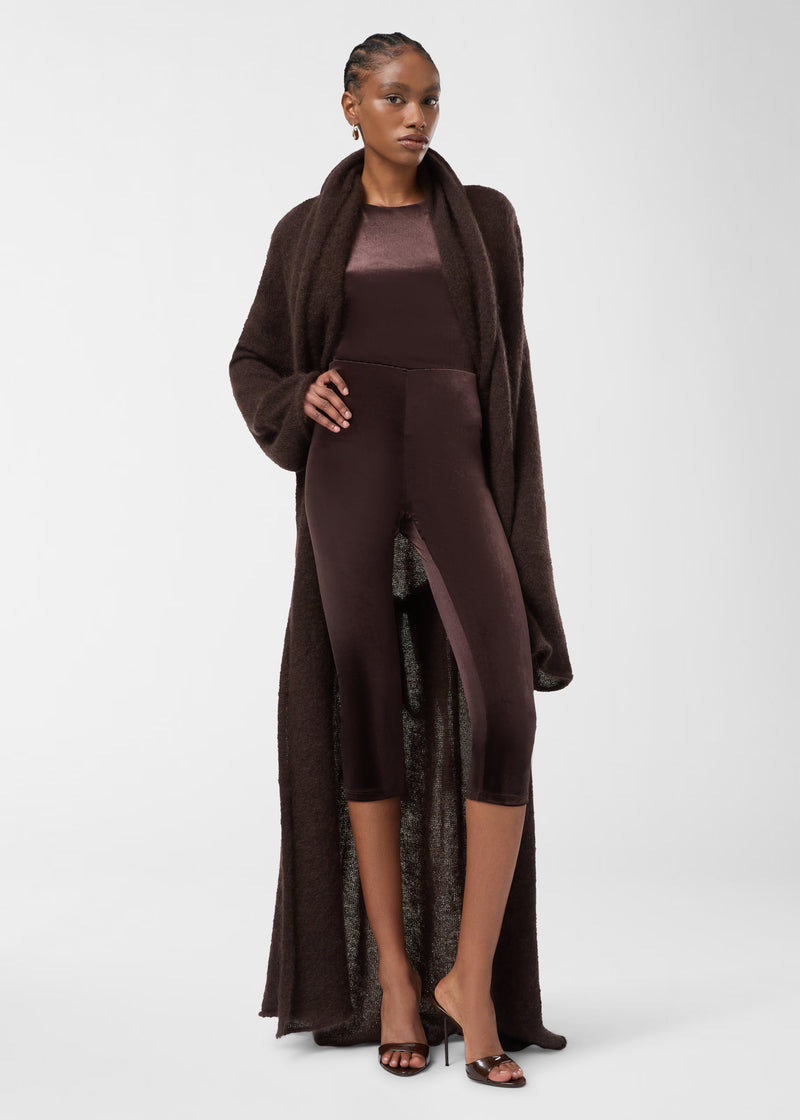 Frontal view: A model wears New Holly Capri Leggings, dark brown high-waisted velvet leggings ending below the knees, styled with a long cardigan and heels.
