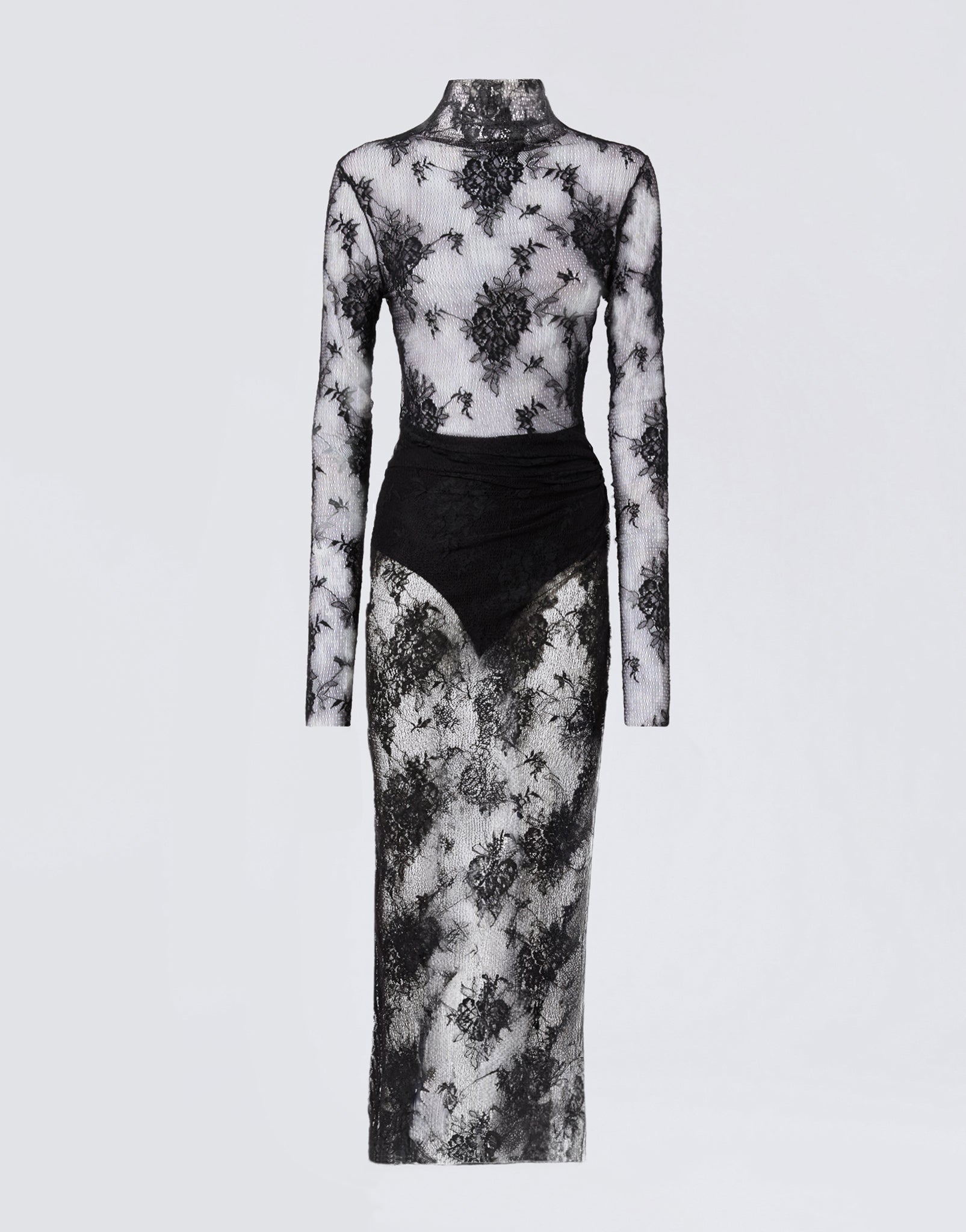 Frontal view of the Tessa Jumpsuit, a sheer black lace jumpsuit with long sleeves, turtleneck, knot detail at the waist, and maxi skirt overlay.