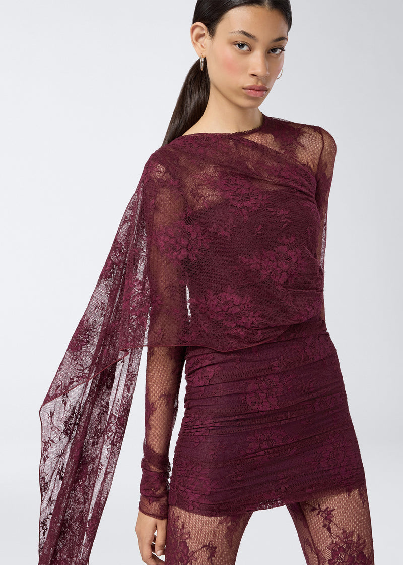 
                          Frontal view showing the Xenia Mini Dress in cabernet lace with sheer and opaque finishes, long sleeves, ruching, and a dramatic cape cascading over the shoulder.
                        