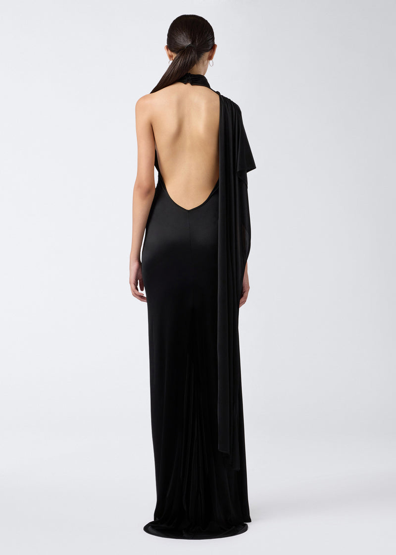 
                          Rear view of a model wearing the Waverly Maxi Dress in black shiny jersey, featuring a cape draped over one shoulder and a low open back.
                        