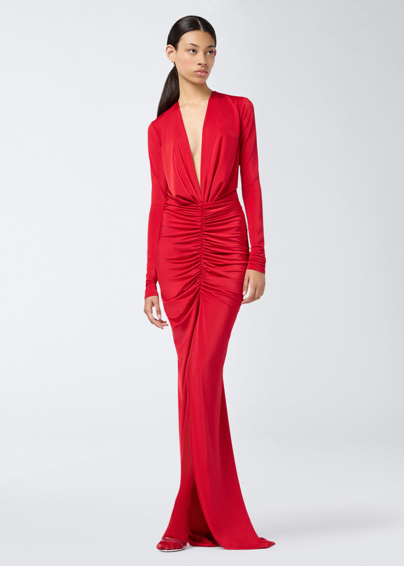 
                          Frontal view shows a model wearing the Zelda Maxi Dress in red. The dress features a plunging V-neck, open back, long sleeves, vertical draping on the bodice, horizontal ruching on the skirt, and a front opening.
                        