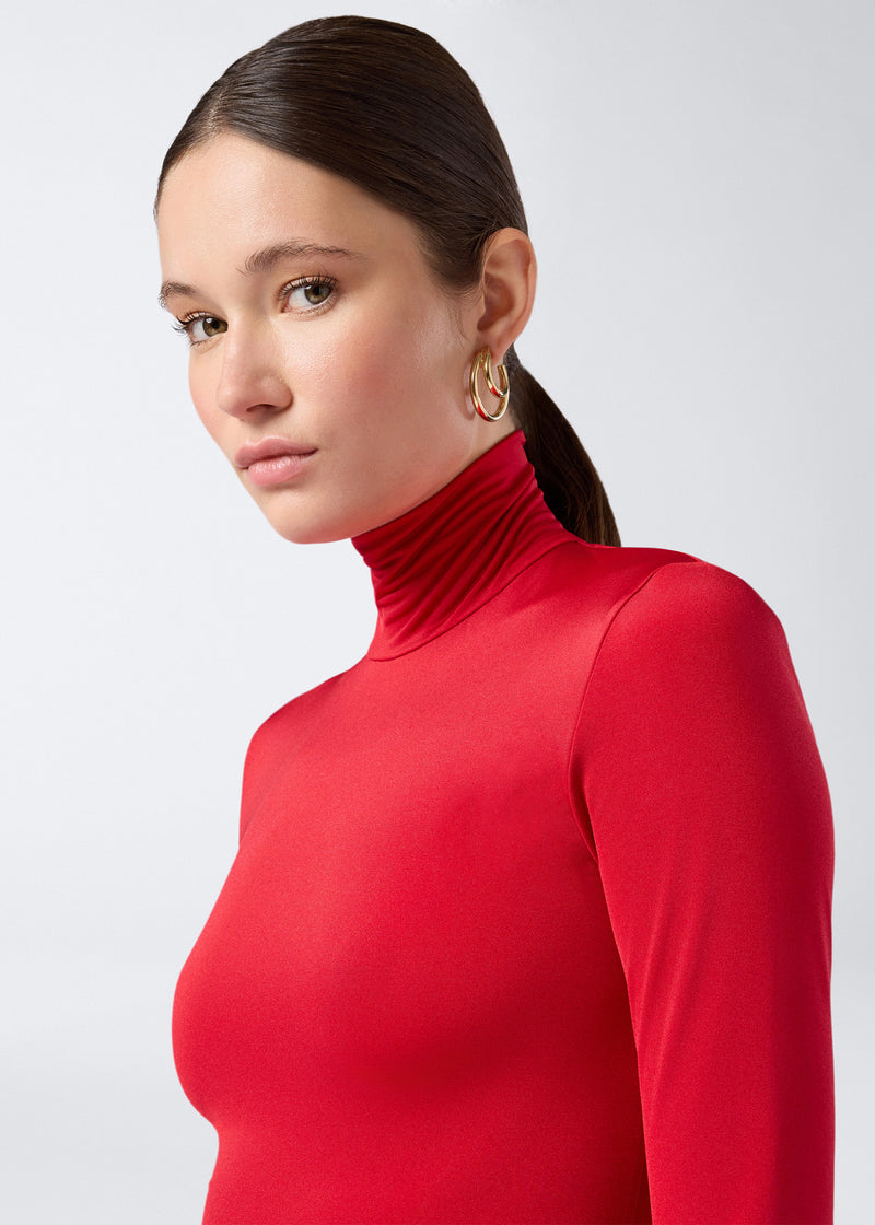 
                          Frontal view shows a woman wearing the Warwick Maxi Dress in red lightweight jersey, featuring a turtleneck and long sleeves with a smooth, fitted silhouette.
                        