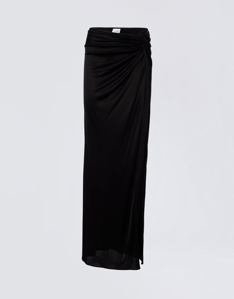 
                          Frontal view shows the Zohra Maxi Skirt in black shiny jersey with high-rise waist, side knot detail, draped design, and ruched back contour.
                        
