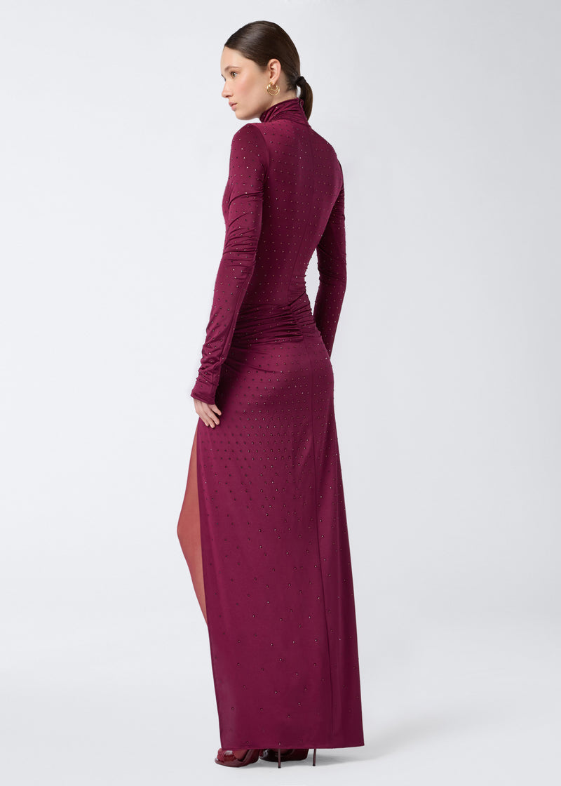 
                          Rear view of a woman wearing the Zohra Crystal Maxi Skirt in cabernet jersey, featuring all-over crystals, side knot detail, and ruching at the back.
                        