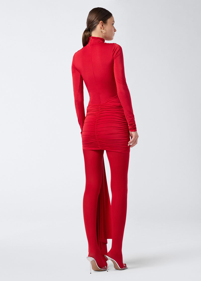 
                          Rear view of a woman wearing the Wendell Mini Skirt in red lightweight jersey, featuring all-over ruching and a long panel detail suspended from the hem.
                        