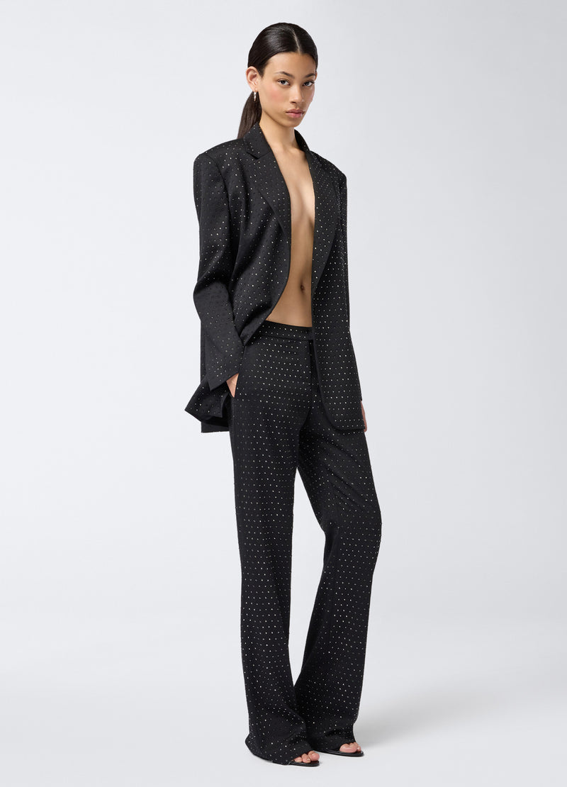 
                          Frontal view of a model wearing Gladys Pants, straight black wool and gabardine pants with all-over crystals and a low waist, styled with a matching blazer.
                        