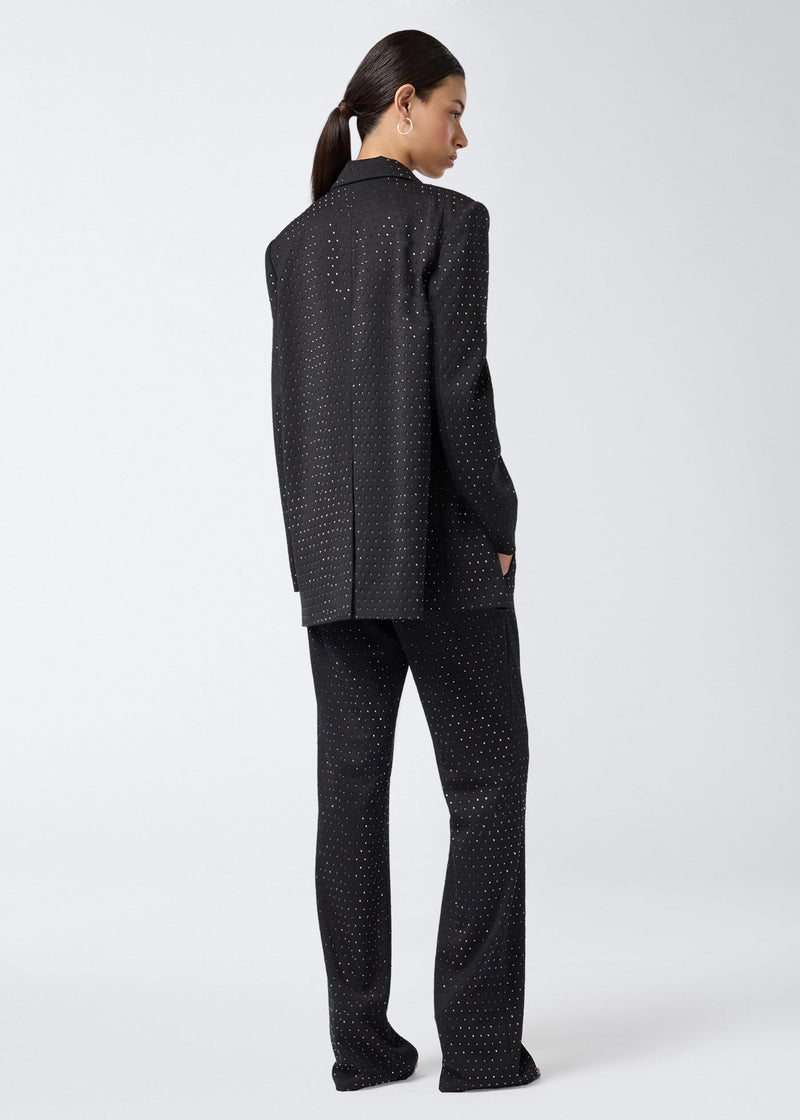 
                          Rear view of a person wearing Gladys Pants, black straight-leg wool and gabardine blend, with all-over crystal embellishments, paired with a matching blazer.
                        