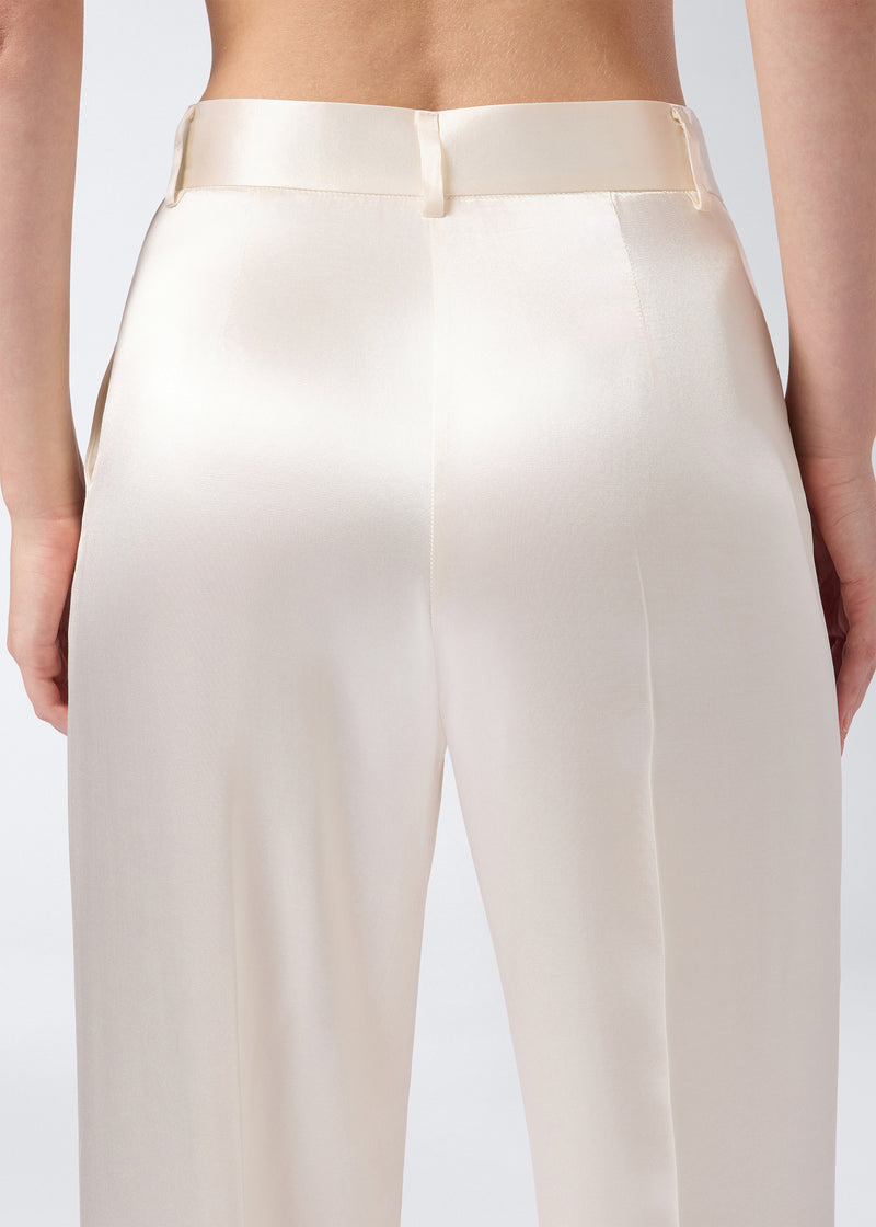 
                          Rear view shows Nathalie Pants in ivory shiny satin, highlighting wide-hem cut, high-rise waist, belt loops, and smooth, shimmering fabric.
                        