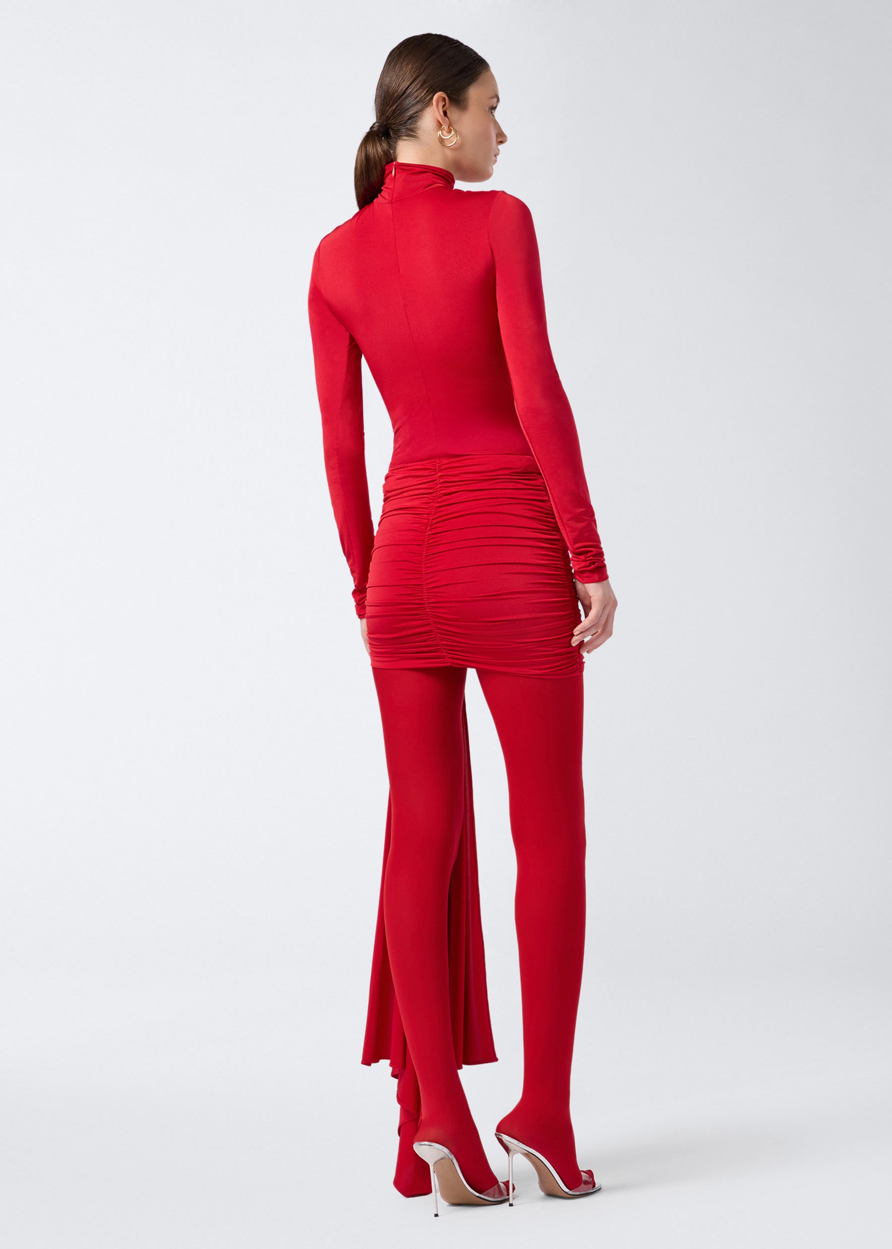 Rear view of a model wearing the Ziggy Bodysuit in red lightweight jersey, featuring a turtleneck, long sleeves, and a fitted, skin-hugging silhouette.