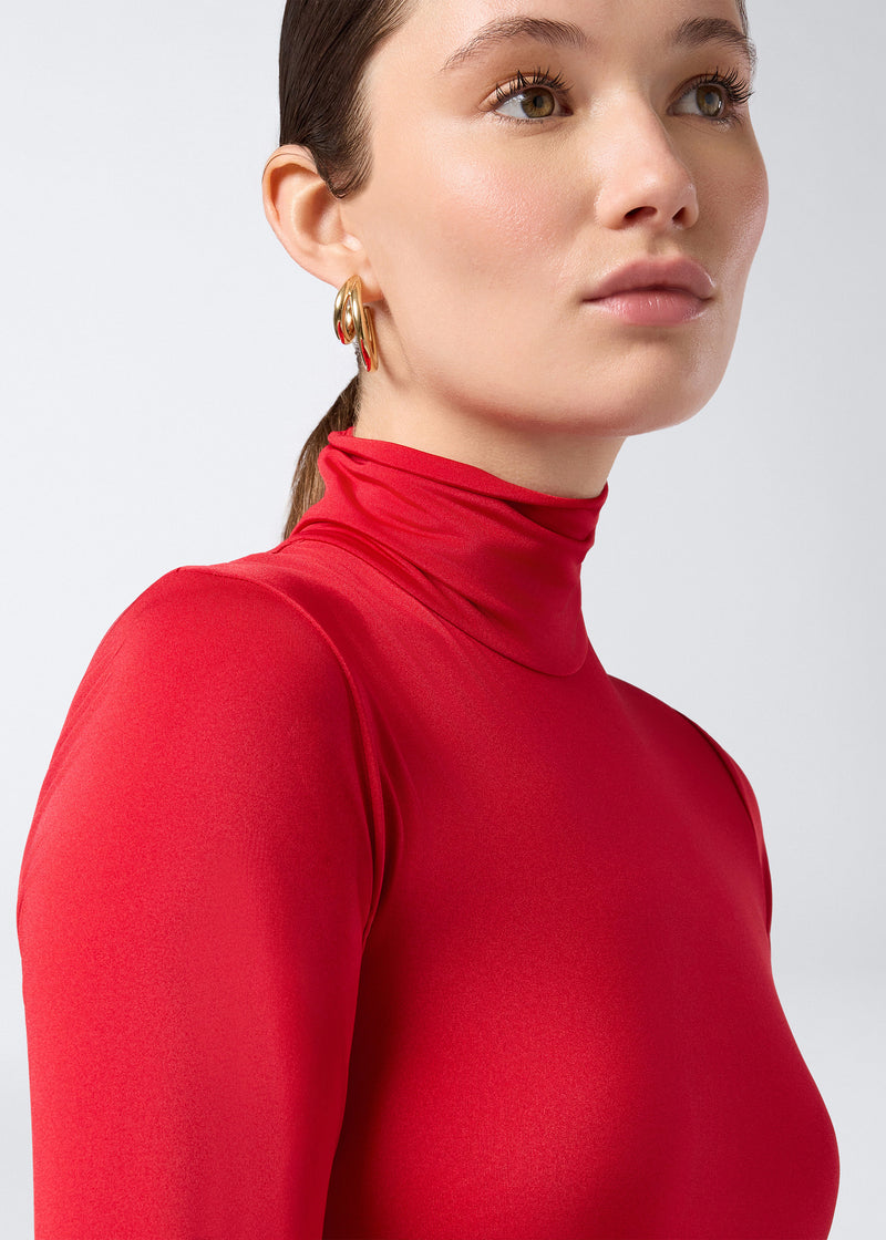 
                          Frontal view of a woman wearing the Ziggy Bodysuit in red lightweight jersey, featuring a turtleneck, long sleeves, and a skin-hugging silhouette.
                        