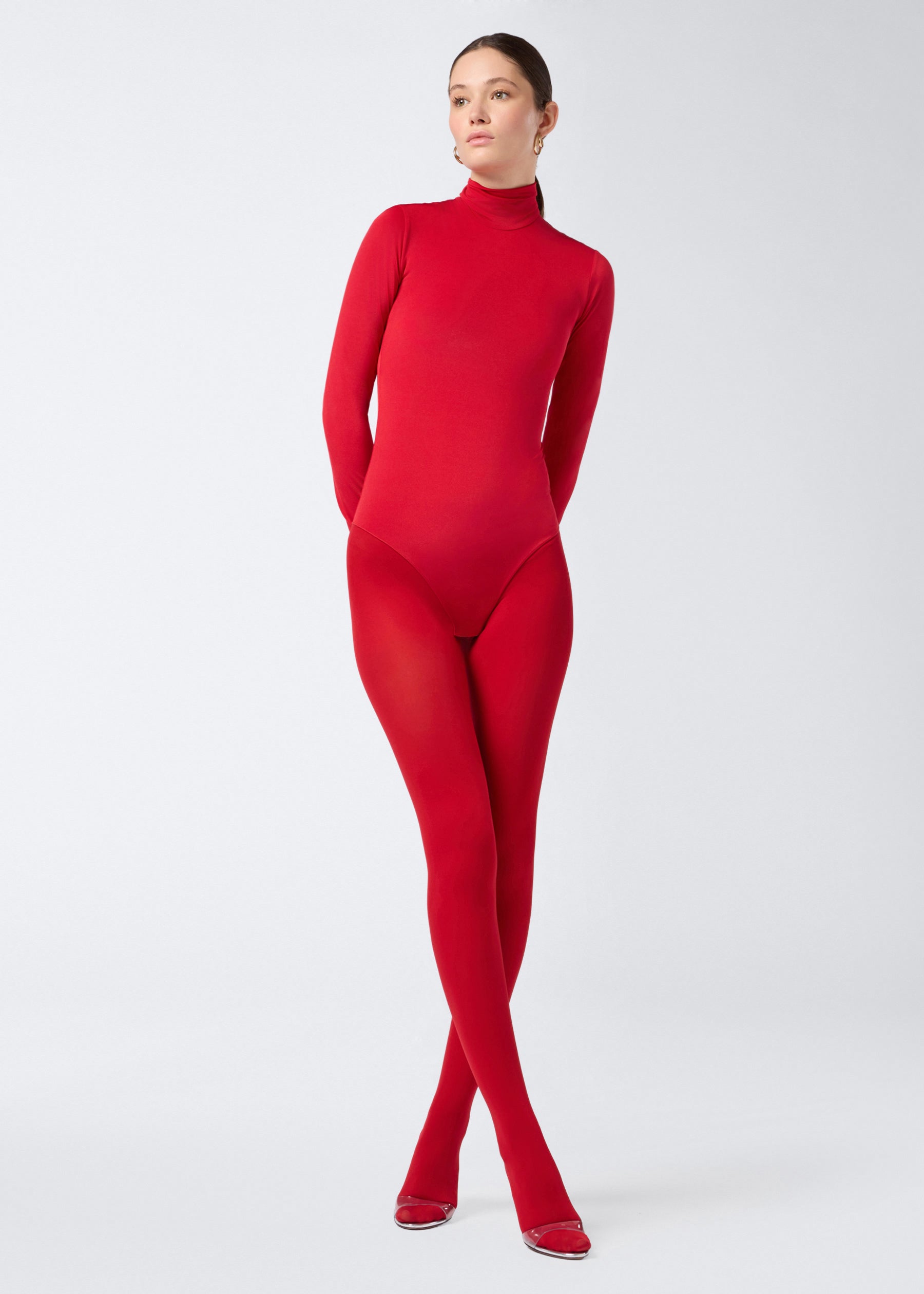 Frontal view of model wearing the Ziggy Bodysuit, a fitted red jersey women&#39;s bodysuit with long sleeves, turtleneck, and zip fastening at the back.