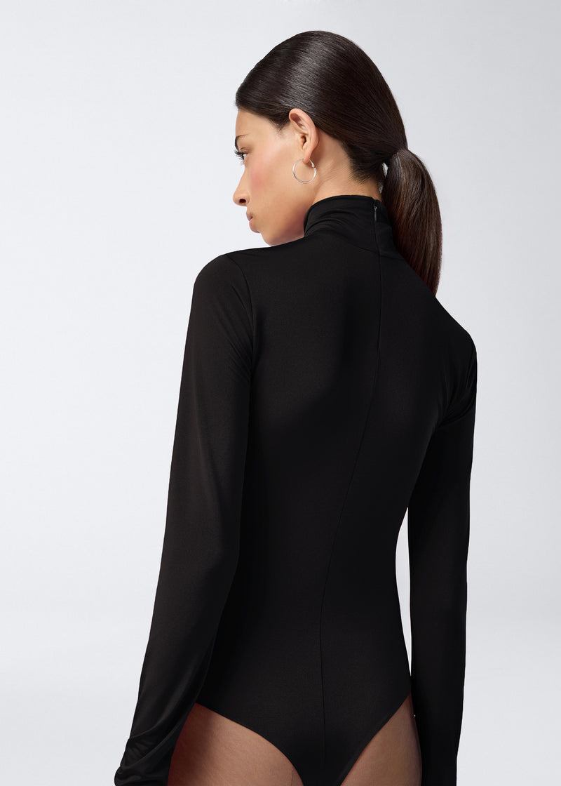 
                          Rear view of a woman wearing the Ziggy Bodysuit in black lightweight jersey, featuring long sleeves, a turtleneck, and a visible zip fastening at the back.
                        