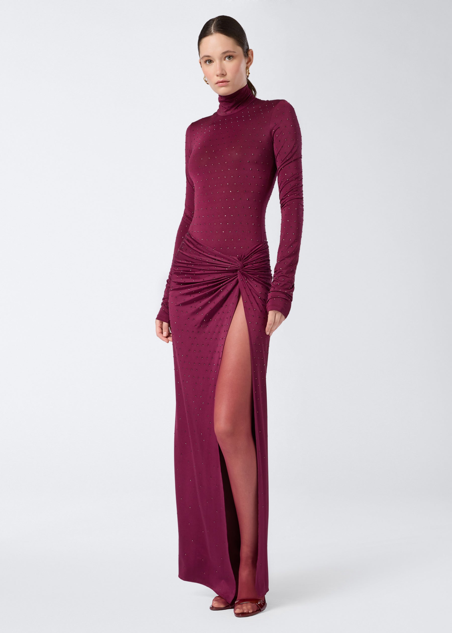 Frontal view shows a woman wearing the Ziggy Bodysuit in cabernet color, featuring long sleeves, a turtleneck, and all-over crystal embellishments.
