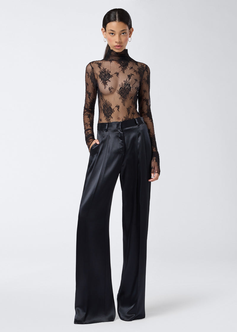 
                          Frontal view of a model wearing the Ziggy Bodysuit, a sheer black lace bodysuit with long sleeves, turtleneck, and back zip closure.
                        