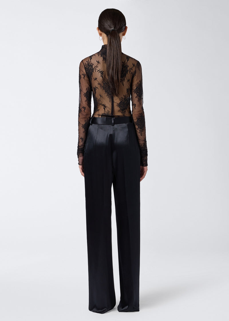 
                          Rear view shows model wearing Ziggy Bodysuit, a sheer black lace, long-sleeve, turtleneck bodysuit, zipped at the back, paired with black satin pants.
                        