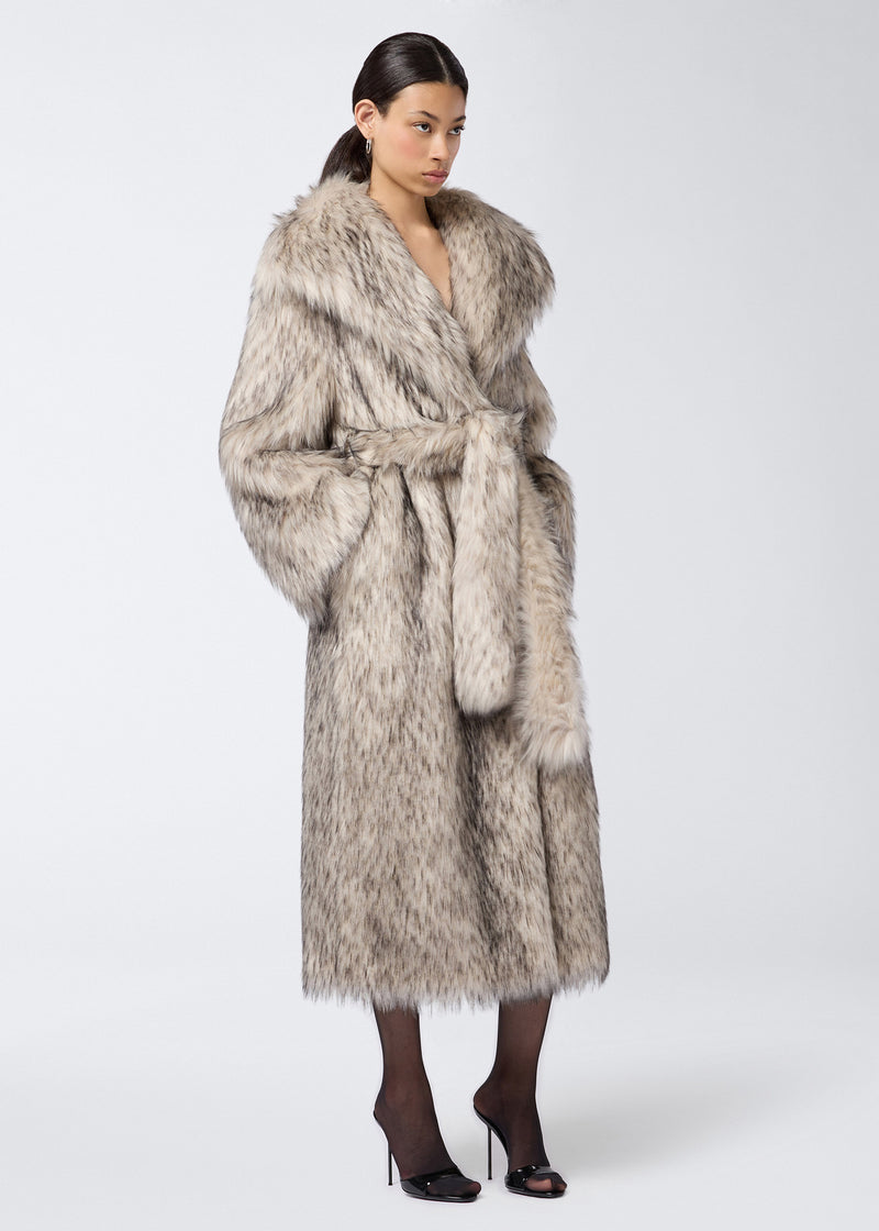 
                          Side view of a woman wearing the Winter Maxi Coat in greige faux fur, featuring an oversized fit, large shawl lapel collar, long sleeves, and a matching belt tied at the waist.
                        