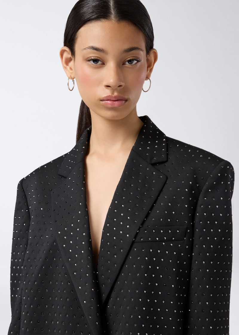 
                          Frontal view of the Guia Blazer, a black oversized women&#39;s blazer with crystal embellishments, notched lapel, padded shoulders, and chest welt pocket visible.
                        