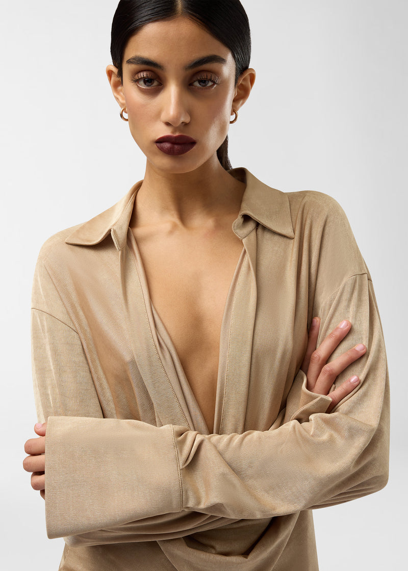 Frontal view — Lilia Mini Dress drapes softly on a model, showing deep plunging V-neck, pointed spread collar, and long exaggerated cuffs in golden jersey.