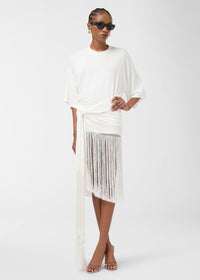 Frontal view: Model wears Azul Midi Dress—off-white crew-neck with butterfly sleeves, gathered knot and long fringe hem—standing with one hand on hip against white studio background.