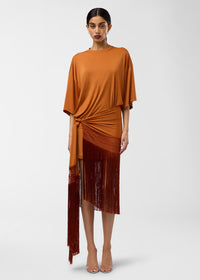 Frontal view — Model wearing Azul Midi Dress standing against a plain background; burnt-orange crew-neck dress with butterfly sleeves, knotted hip detail and long cascading fringe trim.
