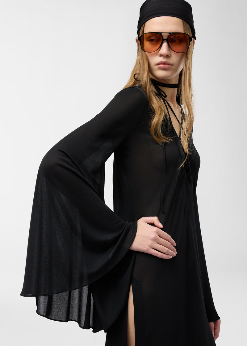 Frontal view — Model in Ava Maxi Dress, black jersey chiffon, shows flowing kimono sleeves, wraparound neck ties forming a chest lattice, and a high side leg slit.