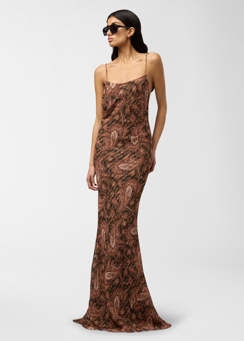 Frontal view — Model wears Ninfea Maxi Dress, standing slightly angled, showcasing brown paisley georgette slip with spaghetti straps, scooped neckline, and long mermaid-effect skirt.